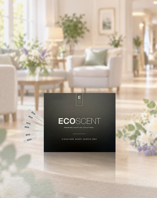 A black ECOSCENT premium setting sample box takes centre stage in the foreground, while several small scent sample cards fan out to the left. Behind it, a softly blurred, bright and elegant care home living room creates a warm backdrop.