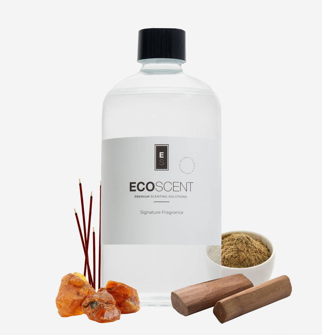 Ecoscent-shop Sandalwood Fragrance Oil in a clear bottle with a black cap, accompanied by sticks and pieces of sandalwood and amber resin. The bottle features the "ECO SCENT" label and a logo.