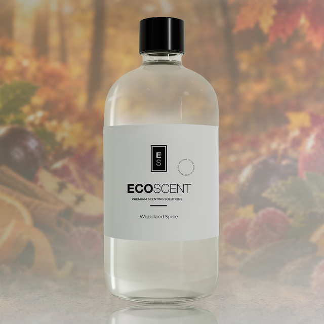 A clear glass bottle of ECOSCENT Woodland Spice premium scented solutions with a white label and black cap, set against a blurred autumn forest background.