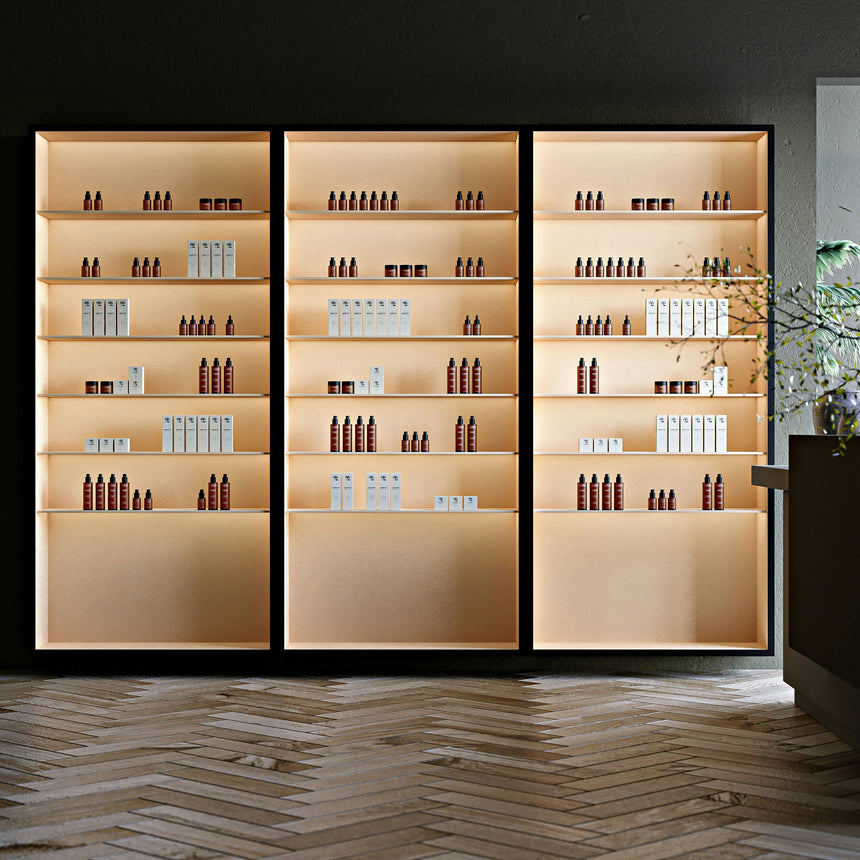 Three illuminated shelves displaying various skincare products, including brown bottles and white boxes, arranged in neat rows against a minimalist backdrop.