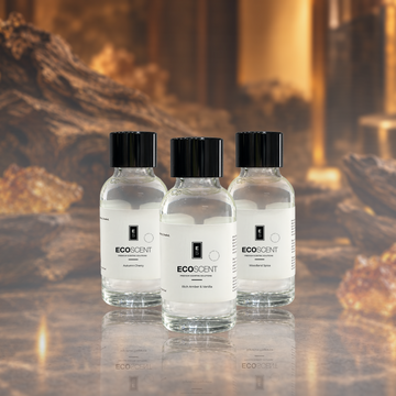 Three clear glass bottles of EcoScent Wood-Based Fragrance Oil with black caps and white labels, arranged on a reflective surface against a warm, blurred background.