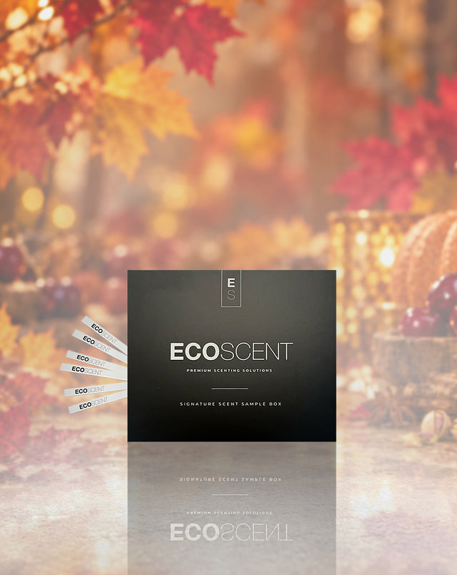 A black ECOSCENT premium scenting solution sample box is centered against a warm autumn background with red and orange maple leaves, glowing lanterns, and pumpkins. Several white sample cards labeled ECO are fanned out to the left.