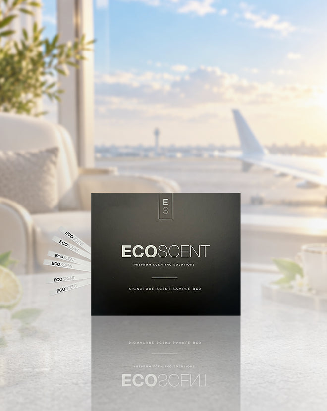A black ECOSCENT premium scenting solution box is displayed on a reflective surface with a blurred airport scene in the background, including an airplane window view and lounge furniture.