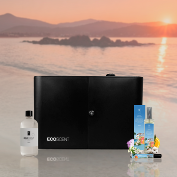 Black scent machine and bottles with 'EcoScent' branding on a beach at sunset.