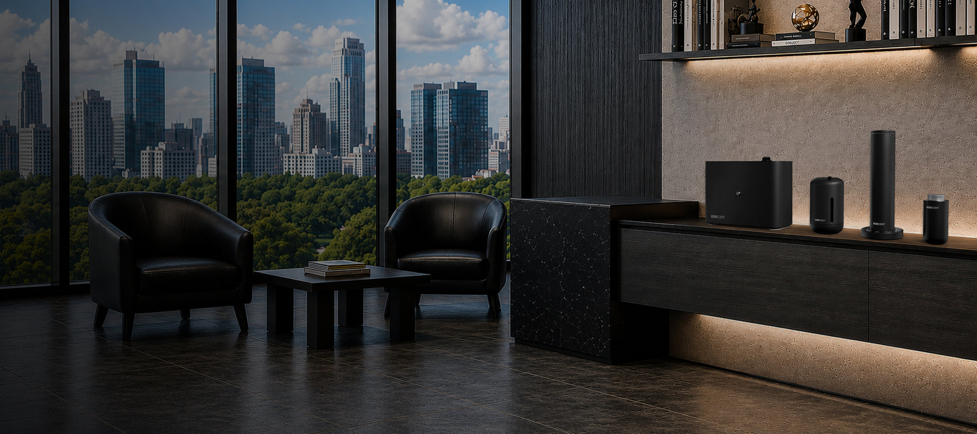 Modern office lounge with two black chairs, a low table holding books, large windows showing a city skyline and park, and shelves with electronics and decor on the right.