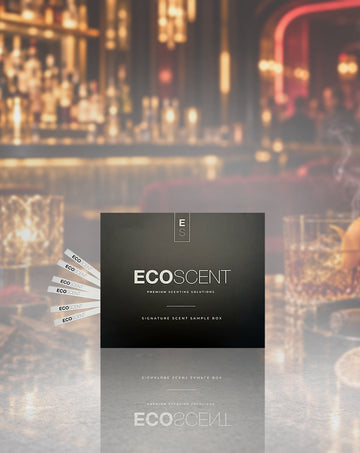 A dark rectangular ECO SCENT product box stands centered in front of a blurred bar scene with warm lights and glasses. Several small sample strips are fanned out to the left on a reflective tabletop.