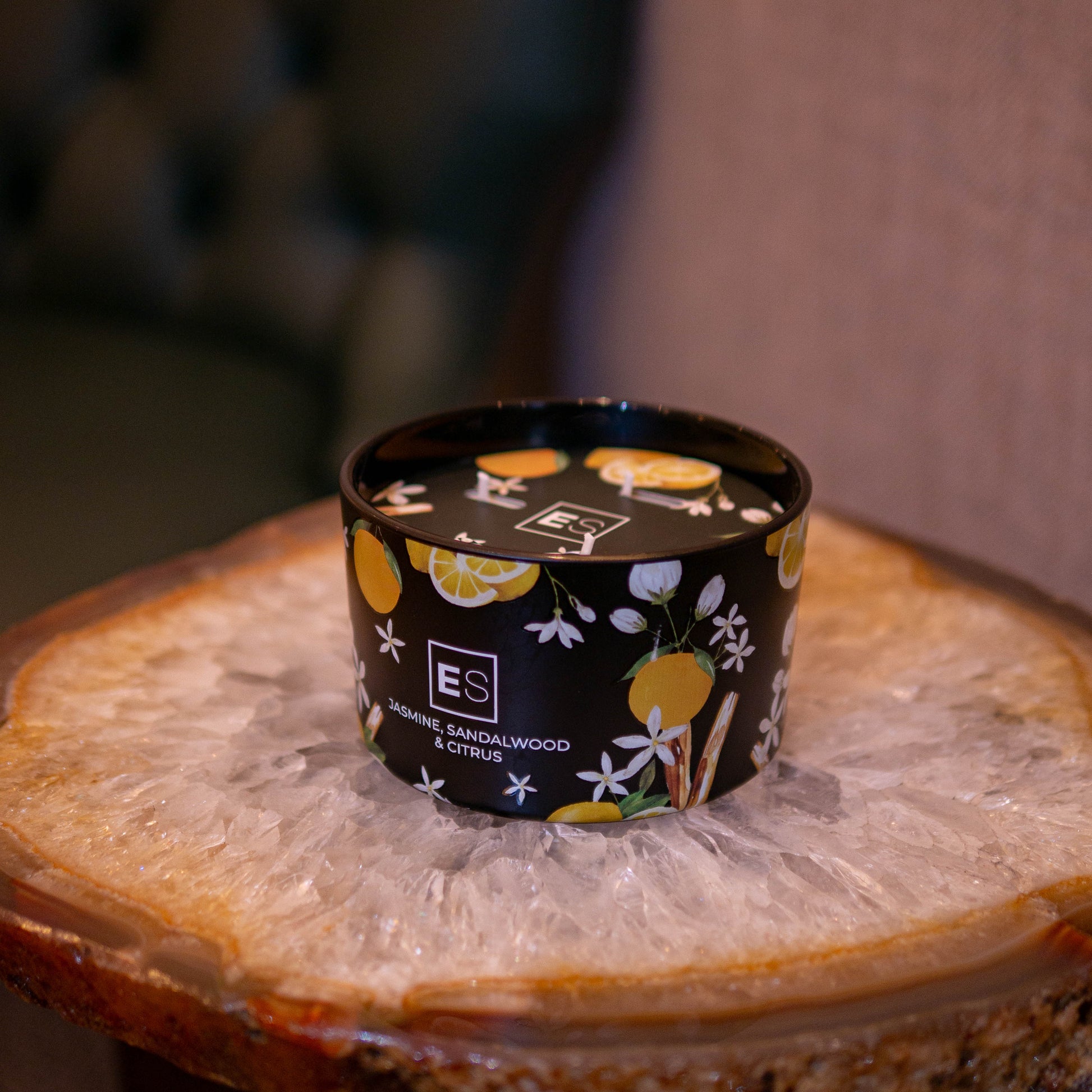 Small container with a black lid featuring floral designs on a wooden surface.