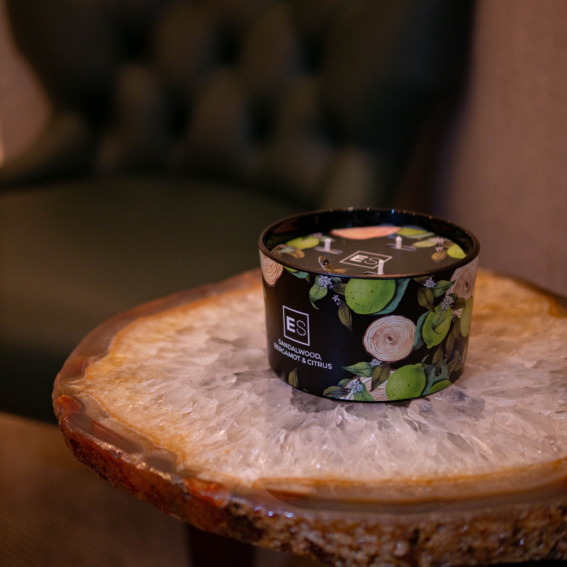 Candle in a decorative container on a wooden table with a blurred background