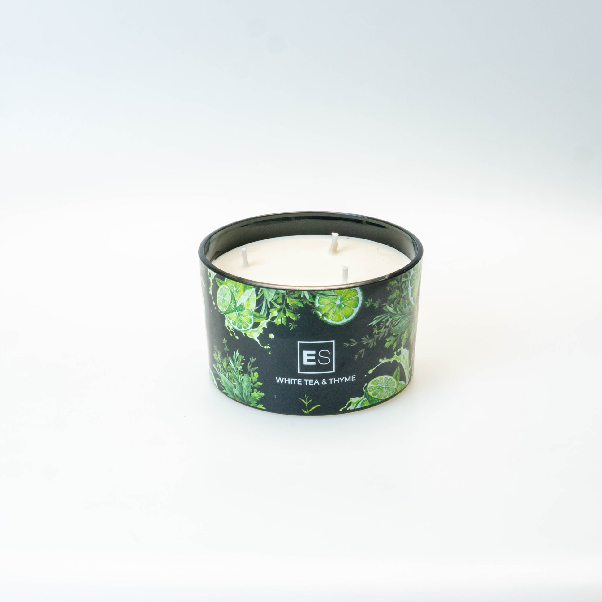 Candle in a green container with a logo on a white surface