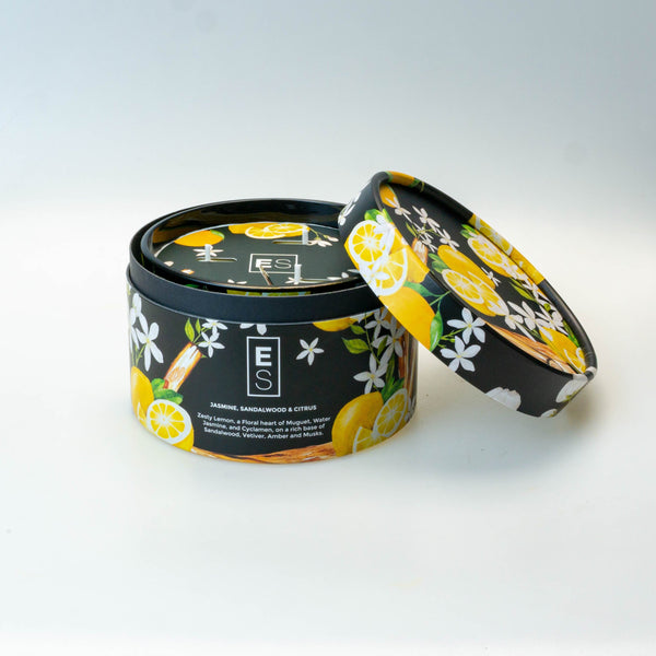 Decorative candle in a black container with floral design on a white surface