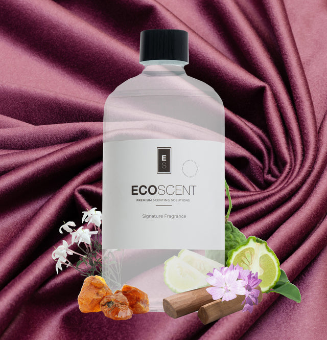 ecoscent-shop Cashmere Silk Blend Fragrance Oil in a clear bottle, featuring a blend of jasmine, sandalwood, and musk scents, displayed against a deep burgundy fabric backdrop with floral and wood elements.