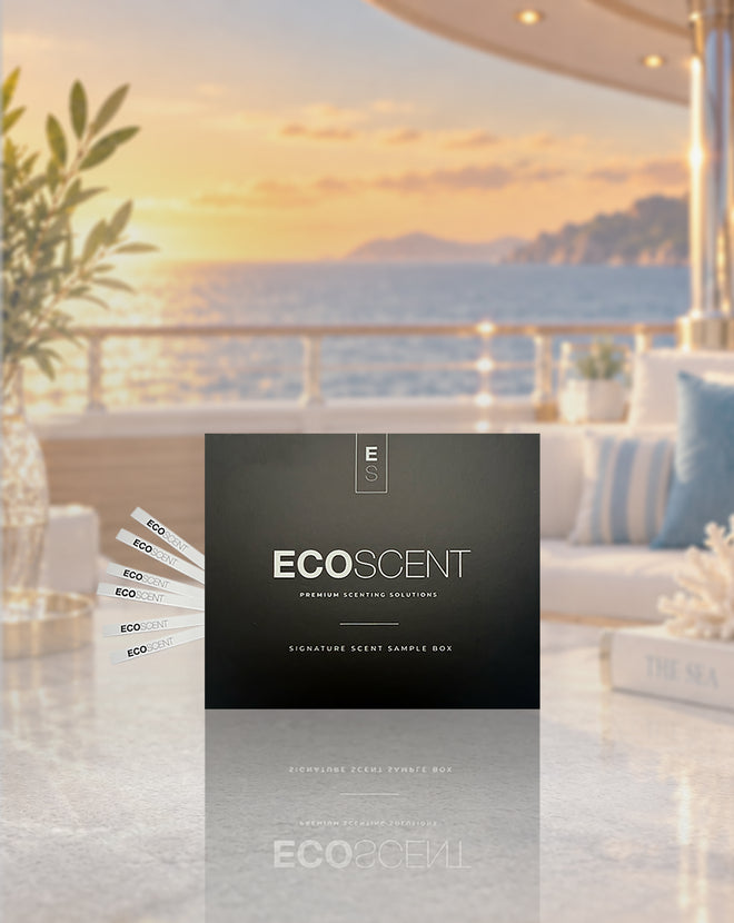 A black ECOSCENT premium setting solution sample box stands on a reflective marble surface in a luxurious outdoor patio setting at sunset, with a sea view in the background and several sample cards fanned out to the left.