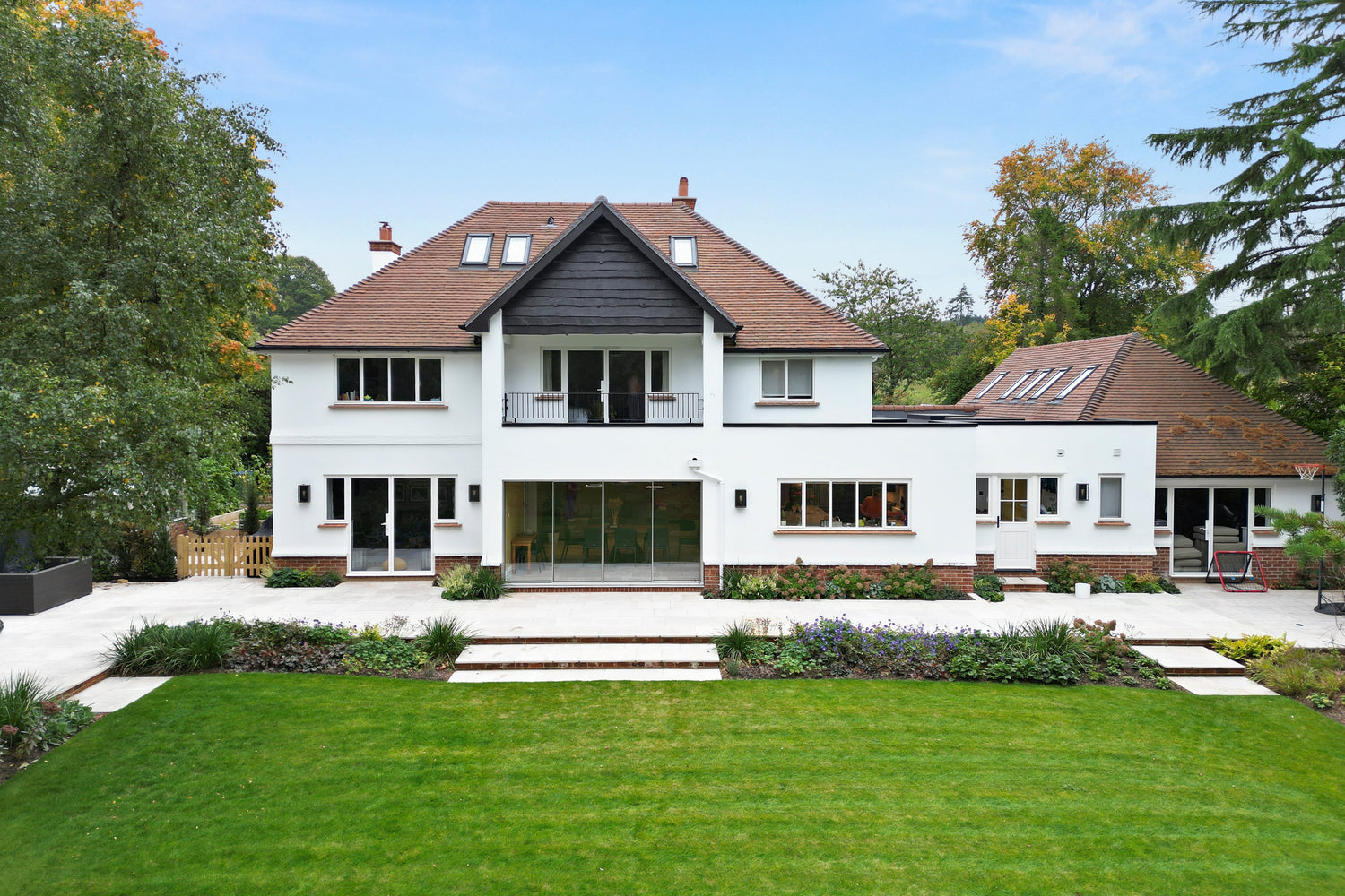 Large white house with a green lawn and trees in the background