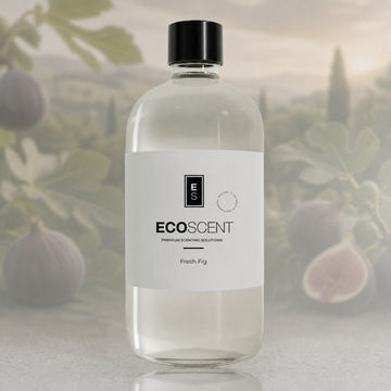 A clear bottle of ECOSCENT Fresh Fig premium fragrance oil with a white label and black cap, set against a soft-focus background of fig plants.