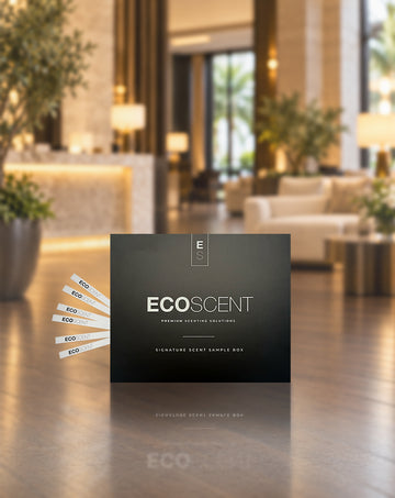 A black ECOSCENT premium scenting solution sample box sits in front.Several white scent sample strips fan out from the left.The background shows a blurred luxury hotel lobby.