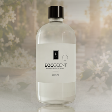 A clear bottle of EcoScent Jasmine fragrance oil with a black cap and white label, set against a softly blurred background of white jasmine flowers and green foliage.