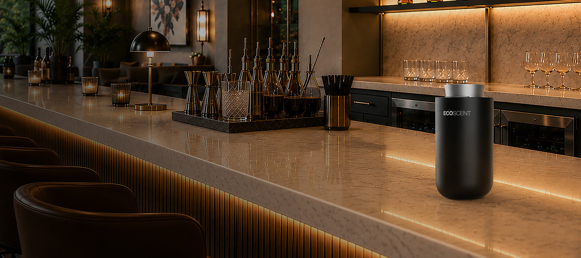 Black ecoscent scent machine on a marble bar counter with barware and glasses, warmly lit, suggesting a cozy upscale bar or lounge setting.