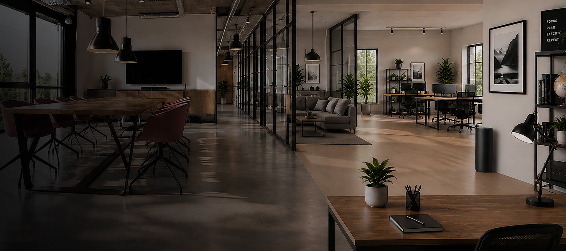 Modern office space with sleek furniture, large windows, and plants, including a conference table, desks, and a cozy lounge area with a TV.
